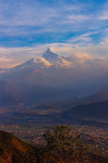 Vista de una alta montaña con cimas nevadas y un pueblo asentado a sus pies