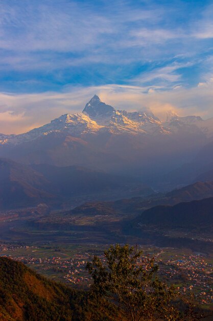 Vista de una alta montaña con cimas nevadas y un pueblo asentado a sus pies