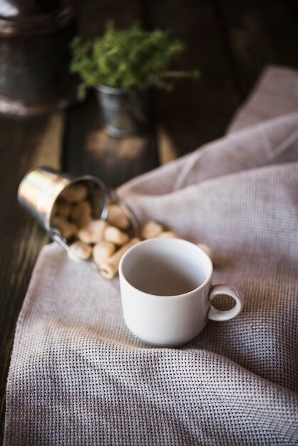 Vista alta taza de café y azúcar sobre tela de arpillera