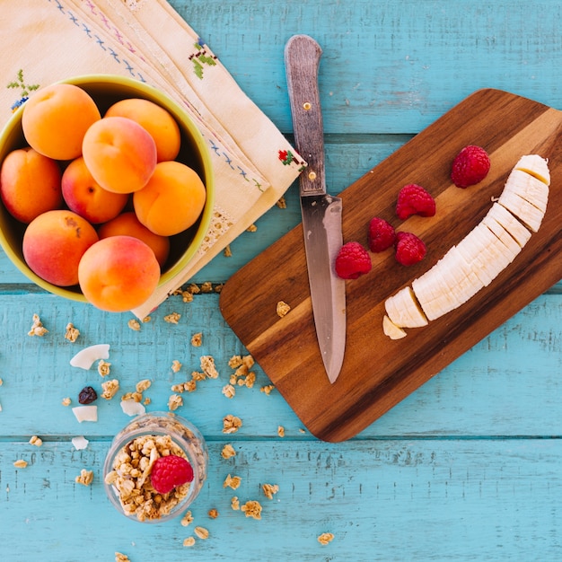 Vista de alto ángulo de rodajas de banana; fresas; melocotón y avena en el fondo de madera azul