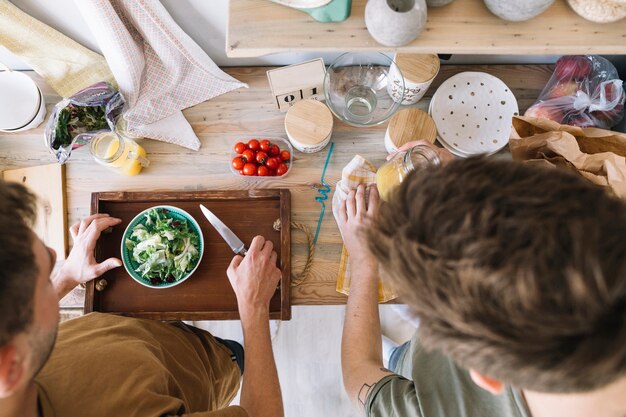 Vista de ángulo alto de amigos haciendo el desayuno en el mostrador de la cocina