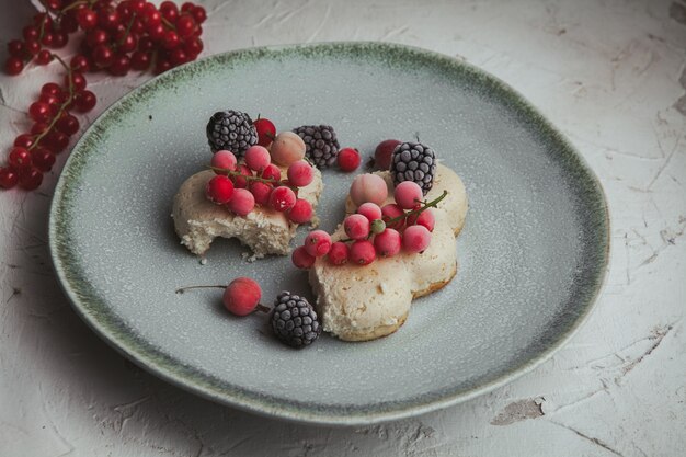 Vista de ángulo alto arándanos en placa con moras, galleta en blanco con textura.