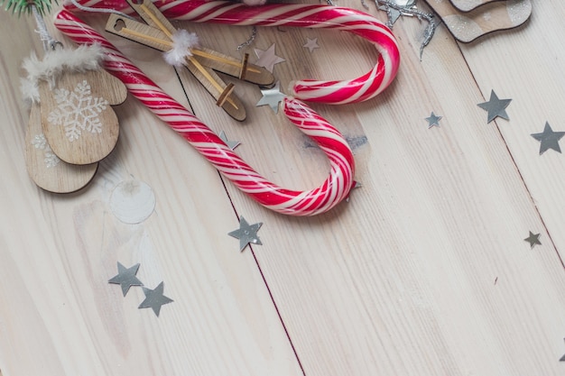 Vista de ángulo alto de bastones de caramelo y adornos navideños en una mesa de madera bajo las luces