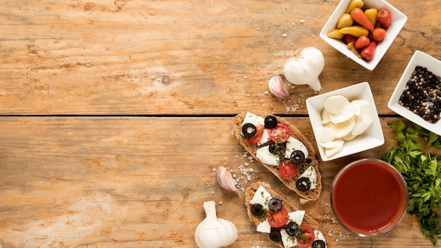 Vista de ángulo alto de bruschetta e ingrediente sobre fondo de madera