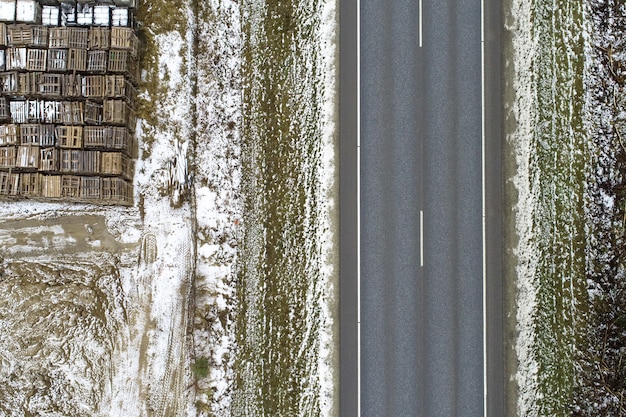 Vista de ángulo alto de una carretera rodeada por un prado cubierto de nieve con objetos metálicos