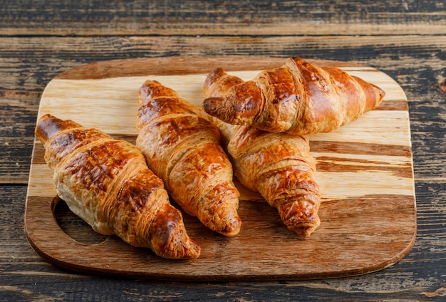 Vista de ángulo alto de croissant en tabla de cortar y madera