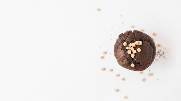 Vista de ángulo alto de cupcake de chocolate con coberturas de caramelos de caramelo sobre fondo blanco