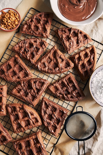 Vista de ángulo alto de deliciosos gofres de chocolate en una red sobre la mesa cerca de los ingredientes