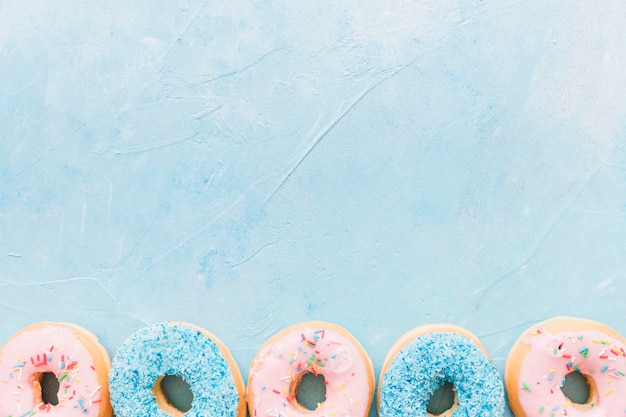 Foto gratuita vista de ángulo alto de donas de colores en la parte inferior de fondo azul