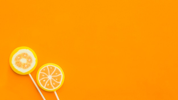 Vista de ángulo alto de dos piruletas en superficie naranja