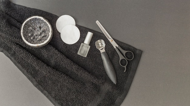 Vista de ángulo alto de exfoliación corporal; esponja; esmalte de uñas; Tijeras y removedor de callos en toalla