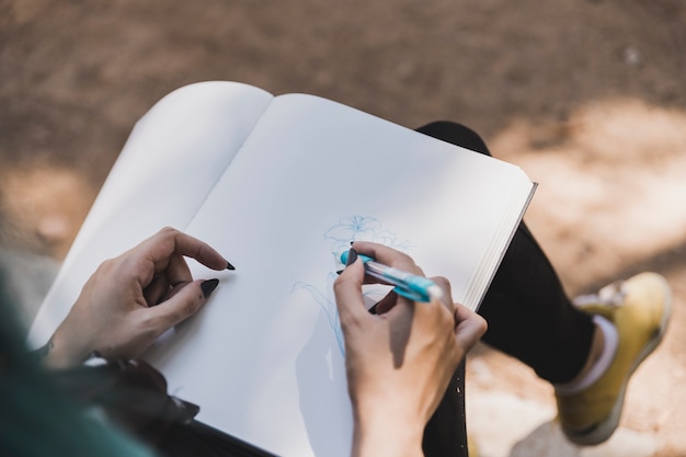 Vista de ángulo alto de flor de dibujo de mujer con pluma azul