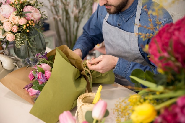 Vista de ángulo alto de florista masculino atar el ramo de flores