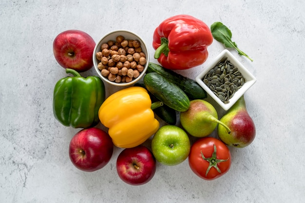 Vista de ángulo alto de frutas coloridas; vegetales; Semillas de calabaza y avellanas sobre fondo