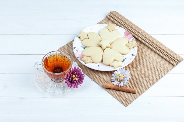 Vista de ángulo alto de galletas en forma de corazón y estrella, flores en mantel con canela