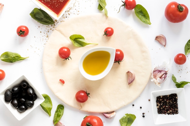 Vista de ángulo alto de ingrediente de pizza cruda sobre fondo blanco