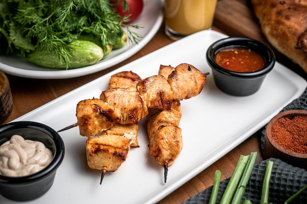 Vista de ángulo alto de kebab de pollo en plato blanco y pimienta de mayonesa ketcup en tazón pequeño