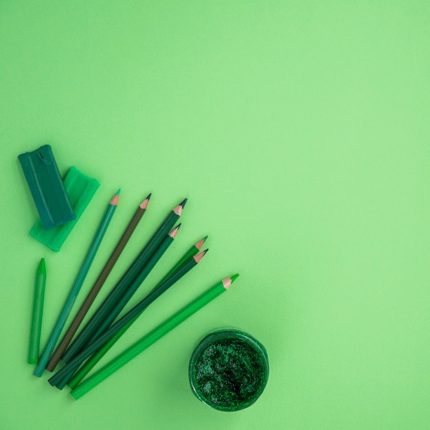 Foto gratuita vista de ángulo alto de lápices de colores; lápiz de color; color arcilla y brillo sobre fondo verde.