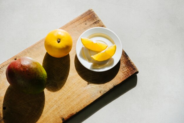 Vista de ángulo alto de lima dulce y mango en la tabla de cortar