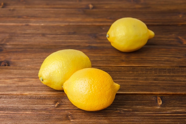 Vista de ángulo alto limones amarillos sobre superficie de madera. espacio horizontal para texto