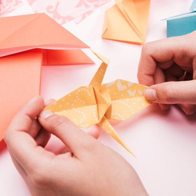 Vista de ángulo alto de la mano del artista sosteniendo origami pájaro de papel