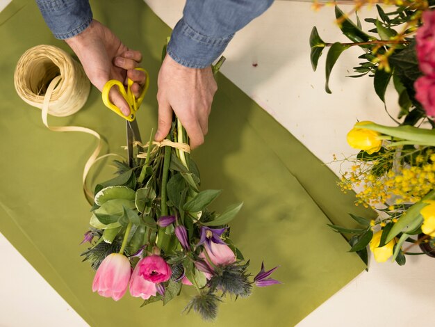 Vista de ángulo alto de la mano masculina de la floristería creando el ramo de flores