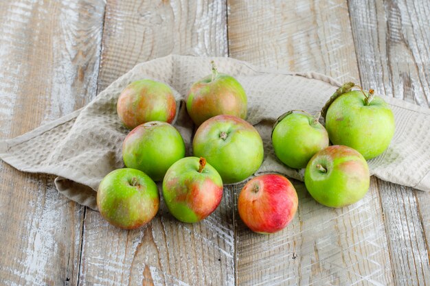 Vista de ángulo alto de manzanas en madera y toalla de cocina