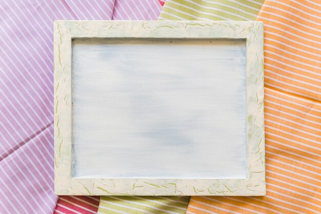 Vista de ángulo alto de marco de fotos en blanco en telas con motivos de rayas
