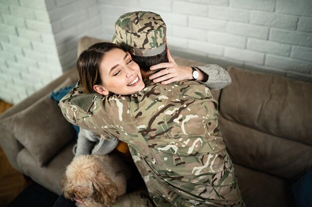 Vista de ángulo alto de mujer feliz abrazando a su esposo militar que llegó a casa del despliegue