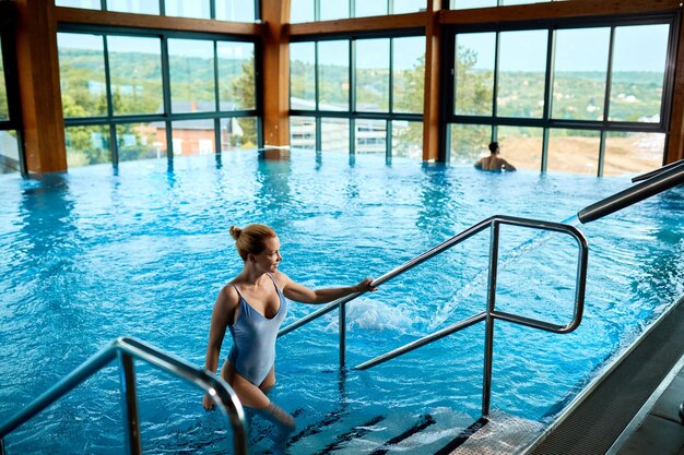 Vista de ángulo alto de una mujer saliendo del agua después de nadar en la piscina en el espacio de copia de spa