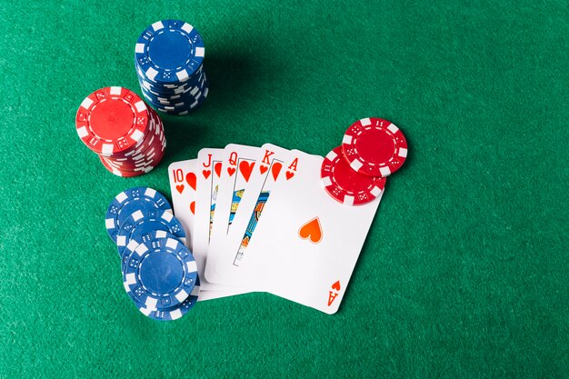 Vista de ángulo alto de naipes de escalera real con fichas de casino en la mesa de póker
