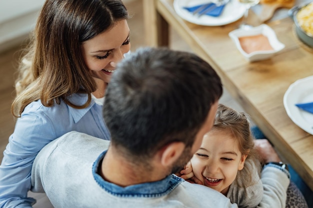 Vista de ángulo alto de niña pequeña divirtiéndose con sus padres en el comedor