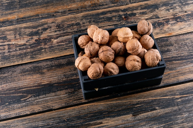 Vista de ángulo alto nueces en caja negra en madera horizontal