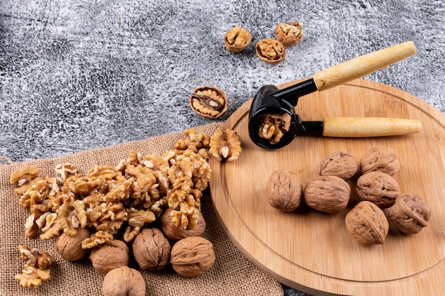 Foto gratuita vista de ángulo alto nueces con cascanueces en tabla de cortar de madera en piedra horizontal