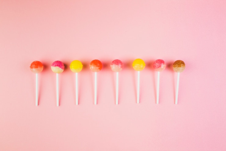 Foto gratuito vista de ángulo alto de paletas de colores en una fila en superficie rosa