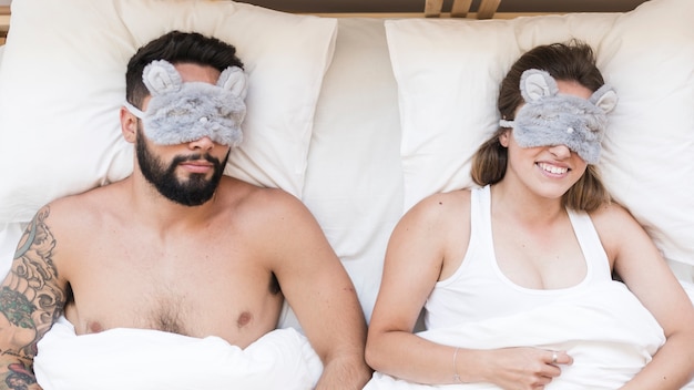 Foto gratuita vista de ángulo alto de pareja durmiendo en la cama con hilo de caramelo