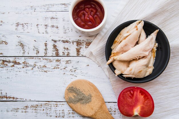 Vista de ángulo alto de pollo hervido con ingredientes en mesa de madera