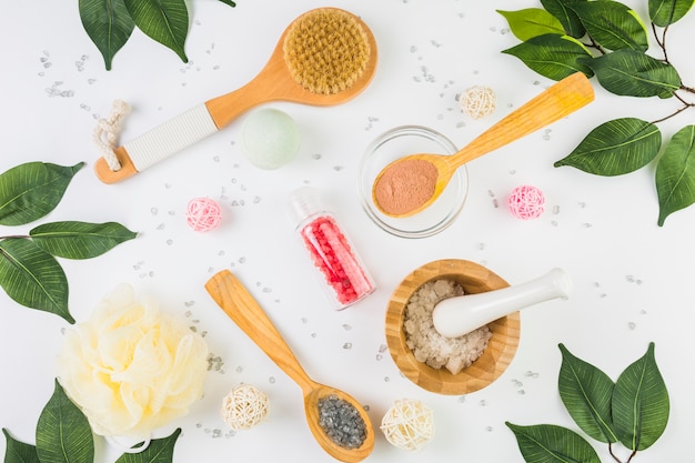 Foto gratuita vista de ángulo alto de productos cosméticos y hojas verdes sobre fondo blanco