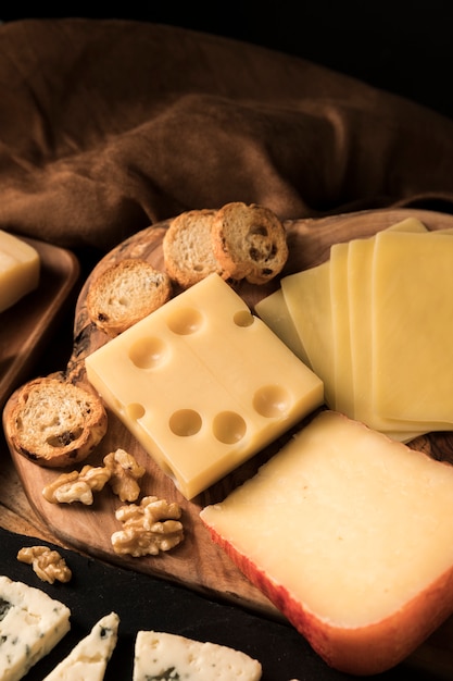 Vista de ángulo alto de queso; Rebanada de pan y nuez en el escritorio de madera