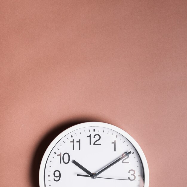Vista de ángulo alto de un reloj de alarma sobre fondo marrón
