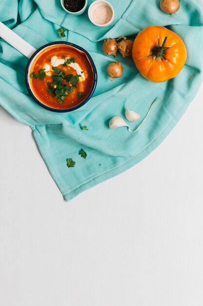 Vista de ángulo alto de sopa de tomate con ajo y cebolla sobre fondo blanco