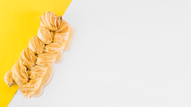Foto gratuita vista de ángulo alto de strudle trenzado y miel sobre fondo blanco y amarillo