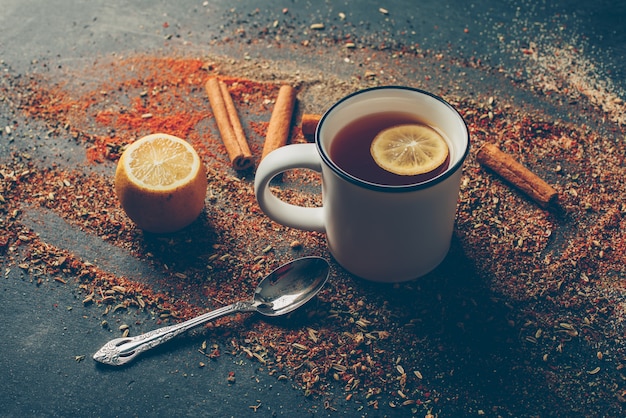 Vista de ángulo alto té de limón y hierbas secas con canela seca, cuchara y limón