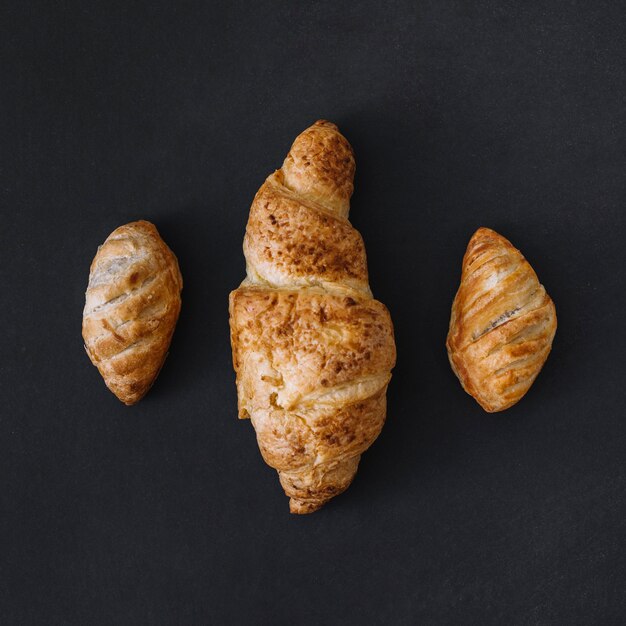 Vista de ángulo alto de tres croissants frescos sobre fondo negro