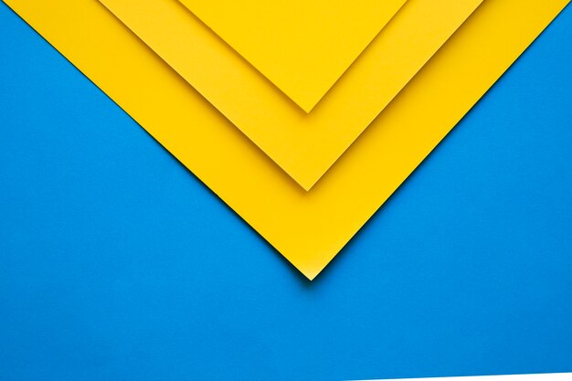 Vista de ángulo alto de tres papeles de cartón amarillo sobre fondo azul