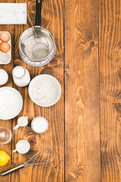 Foto gratuita vista de ángulo alto de los utensilios e ingredientes para hornear para preparar galletas dispuestas en una mesa de madera