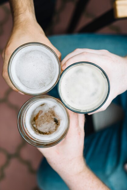 Vista de ángulo alto del vaso tostado de bebidas alcohólicas de un amigo masculino