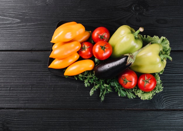 Vista de ángulo alto de verduras crudas saludables en superficie de madera negra