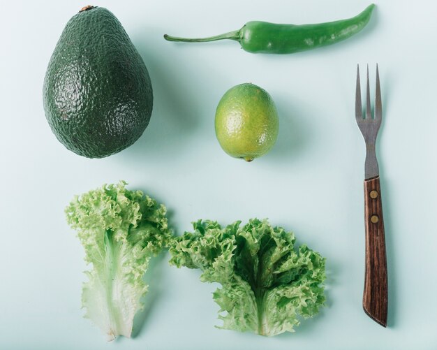 Vista de ángulo alto de verduras frescas con un tenedor en superficie verde