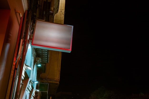 Foto gratuita vista de ángulo bajo de cartelera iluminada en edificio residencial contra el cielo